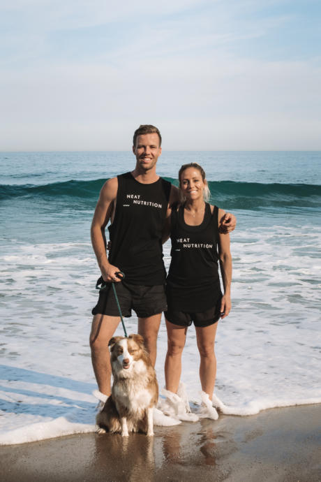 Neat Nutrition business owners with their dog standing in water at beach