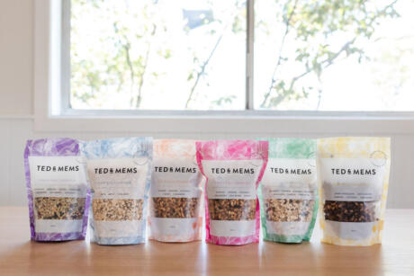 Colourful Ted and Mems branded stand up pouches on bench with white background